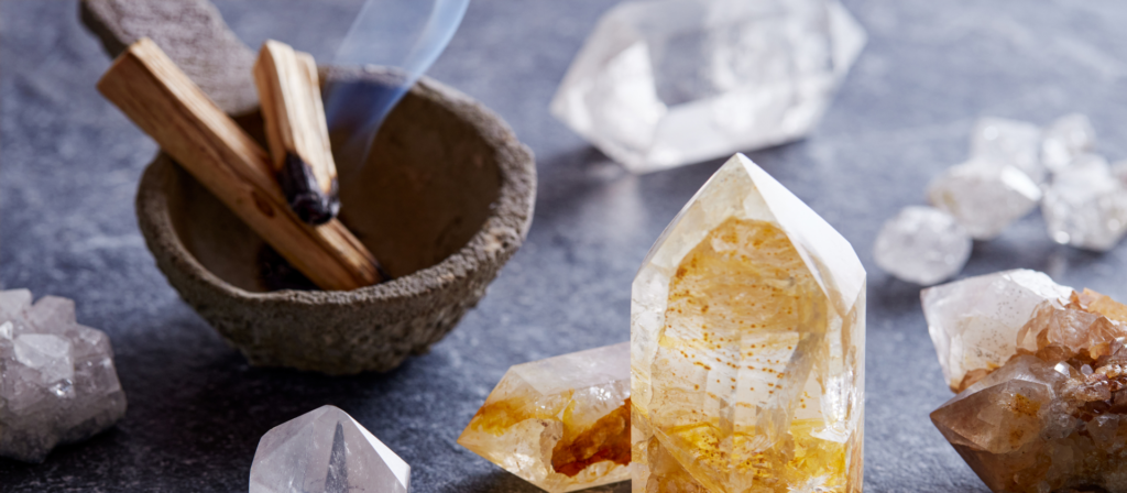 Bâtons de Palo Santo fumant dans un bol avec des cristaux de quartz et de citrine