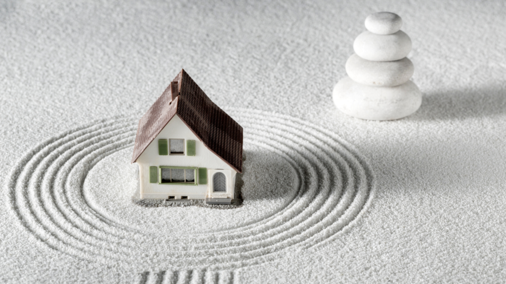 Maquette de maison entourée de cercles tracés dans le sable, symbolisant l'harmonie et l'équilibre énergétique